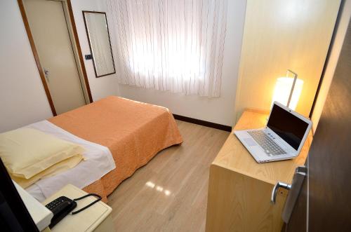 梅斯特圣朱利亚诺酒店的酒店客房配有一张床铺和一张书桌上的笔记本电脑