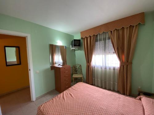 萨洛Apartamento cerca de playa的一间卧室配有一张床、一个梳妆台和一扇窗户。