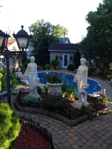 蒙特利尔Chez dany的花园内三个雕像,旁边是游泳池