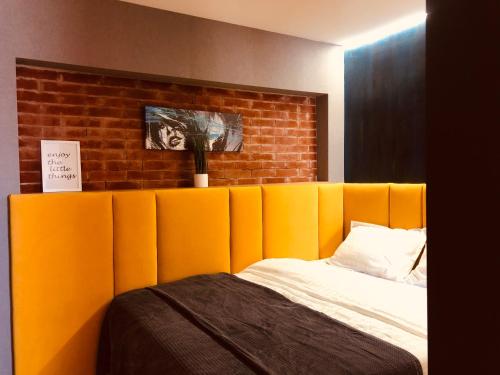雅西GoConcept Studio的砖墙旁的一张带橙色软垫床头板的床