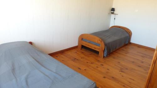 Pertheville-NersMaison de la Delle的一间卧室设有两张床,铺有木地板
