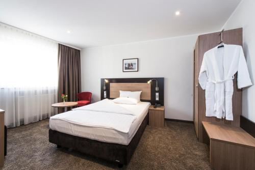 科隆Astor & Aparthotel的酒店客房,配有一张床和一件挂在墙上的长袍