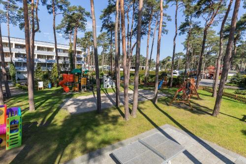 济夫努夫Jantar Medical Spa的一座公园,公园里设有种有树木的游乐场和一座建筑