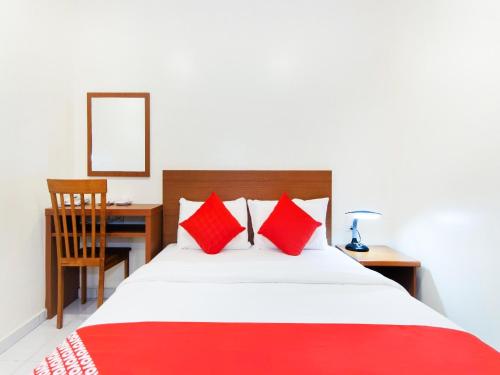 马六甲Lawten Hotel的一间卧室配有一张带红色枕头的床和一张书桌