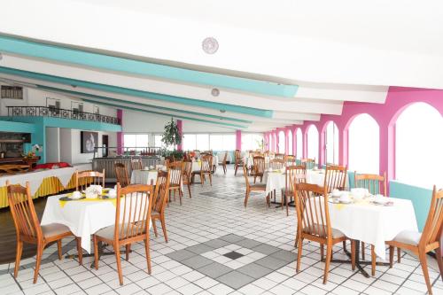 韦拉克鲁斯Grand Hotel KYRIOS Veracruz的餐厅设有白色的桌椅和窗户。