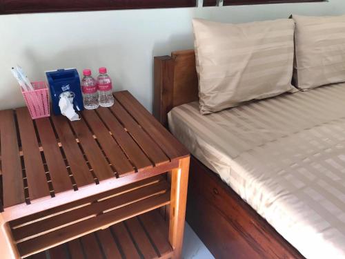 森莫诺隆Manel Guesthouse and Restaurant的一间卧室配有床和一个带瓶装水的长凳