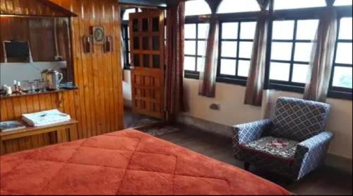 甘托克Tip Top Gujarati House的一间卧室配有一张床、一把椅子和窗户。