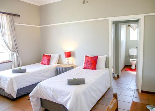 塔巴津比Hardekool Guesthouse的一间卧室配有两张带白色床单和红色枕头的床。