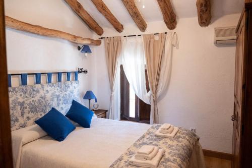 Los NavalucillosCasa Rural los Enebros的一间卧室配有一张带蓝色枕头的床和一扇窗户。