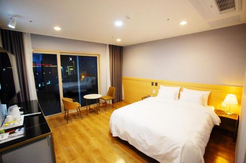 光阳Hotel Haemaru的卧室配有白色的床和桌椅