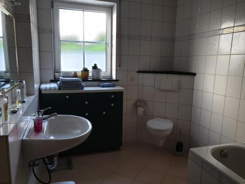 MüdenFerienwohnung Thönnes的一间带水槽和卫生间的浴室以及窗户。