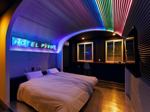 大阪Hotel Pivot Shin-Imamiya Ekimae的一间卧室配有一张带 ⁇ 虹灯标志的床