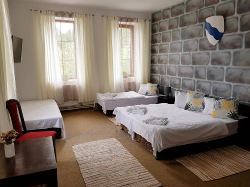蒂萨Hotel Camelot的一间带两张床的卧室和一间带两把椅子的房间