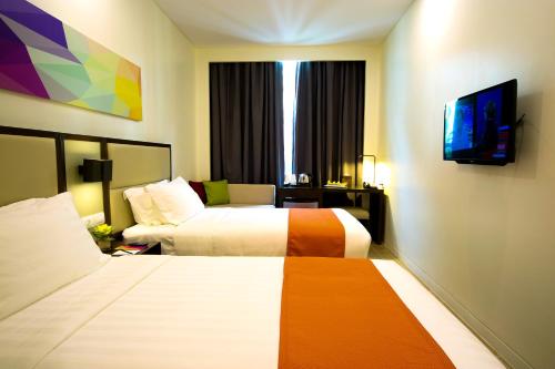 马尼拉Hotel Lucky Chinatown的一间酒店客房,设有两张床和电视