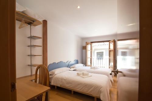 巴利亚多利德Pucela apartmets的一间卧室设有三张床、一张桌子和一个窗户。