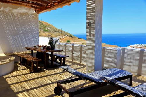 Mandrakia爱琴海蓝色度假屋的木甲板配有桌子,享有海景