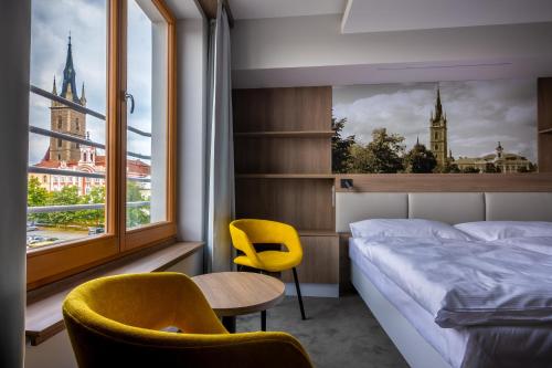 恰斯拉夫Hotel Grand的一间卧室配有一张床、两把椅子和一个窗户