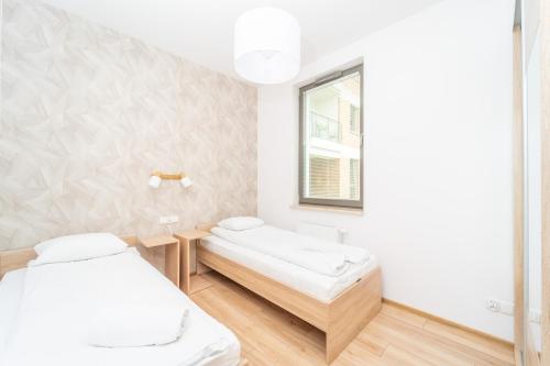 格但斯克Golden Apartments Garden Gates的白色的客房设有两张床和窗户。