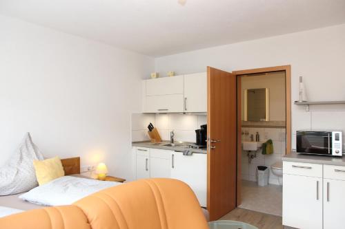 梅德巴赫施魏因博格公寓式酒店的一间设有一张床的客房和一间带白色橱柜的厨房