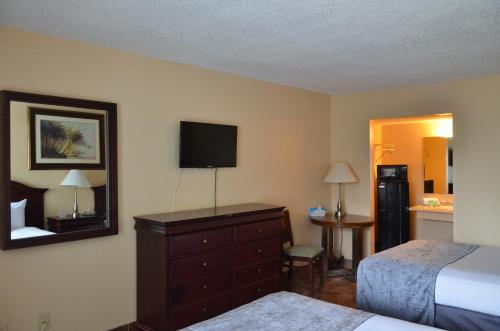 奥兰多Altamonte Springs Hotel and Suites的一间卧室配有一张床和一个带电视的梳妆台