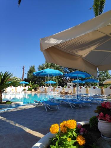 弗尔卡Estia hotel的一个带蓝伞和桌椅的游泳池
