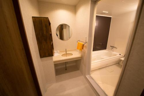洲本市城市海月酒店的一间带水槽、浴缸和镜子的浴室
