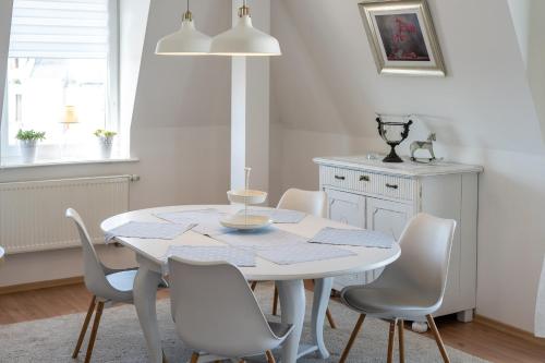 米兹多洛杰马里纳酒店的白色的用餐室配有白色的桌椅