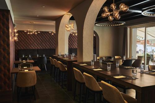 阿斯科纳阿斯科纳广场餐厅酒店 的餐厅设有长桌、椅子和吊灯