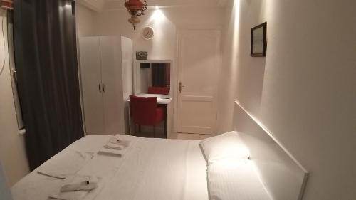 伊斯坦布尔Görkemli Hotel的白色卧室配有白色的床和红色椅子