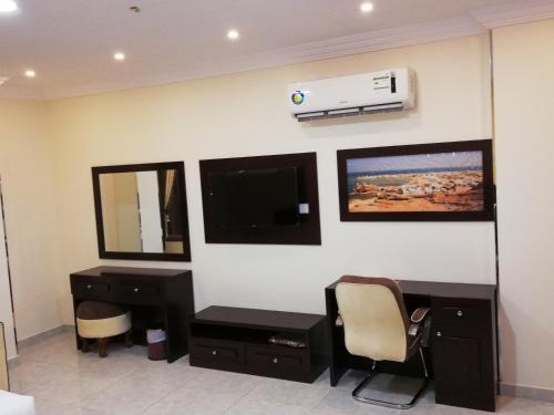 阿尔布亚米Alsafa Hotel的客房设有书桌和墙上的电视