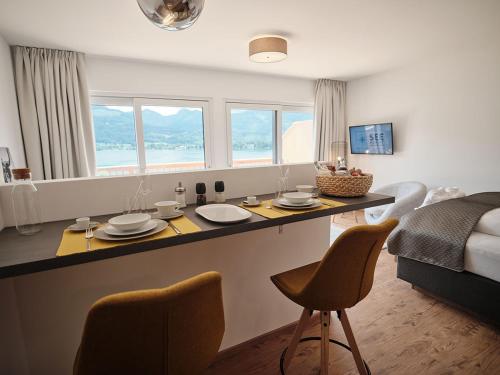 圣沃尔夫冈SEE Moment Appartements ADULTS ONLY的厨房以及带桌椅的起居室。