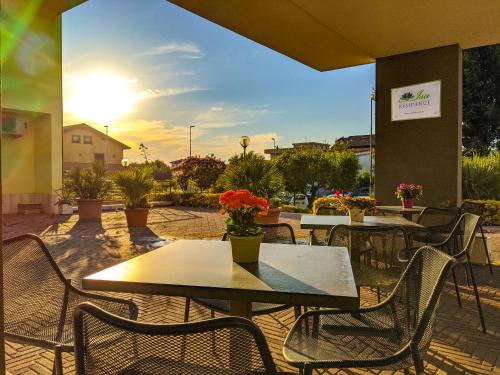菲乌米奇诺Isa Residence Fiumicino Airport的一个带桌椅的庭院,享有阳光