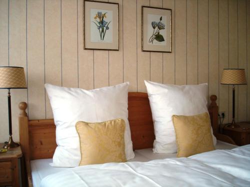 萨尔布吕肯贝利斯切沃尔夫萨尔布吕肯酒店的一张带白色枕头的床和墙上的两张照片