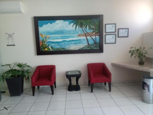 图斯潘罗德里格斯卡诺加利福尼亚酒店的一间设有两张红色椅子和墙上一幅画的等候室