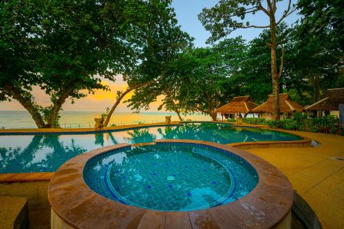 象岛暹罗海滩度假酒店的一座大型游泳池,旁边是大海,设有一张木桌