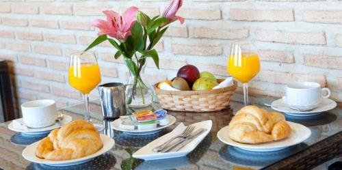 托莱多托雷多老城酒店的一张桌子,上面放着羊角面包和一篮水果及橙汁