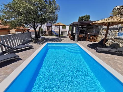 拉布Vila Marija的蓝色游泳池配有椅子和遮阳伞