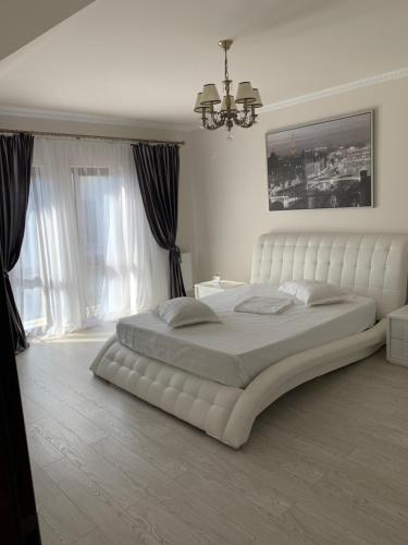 普洛耶什蒂Vila Pati的白色的卧室设有一张白色大床和一个窗户。