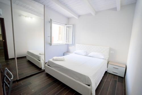 卡坦扎罗Garden House的白色卧室配有床和镜子
