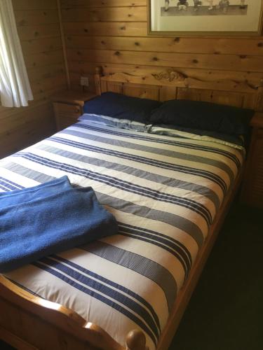 泰恩德拉姆Chalet 2的木制房间的一个床位,上面有蓝色的毛巾