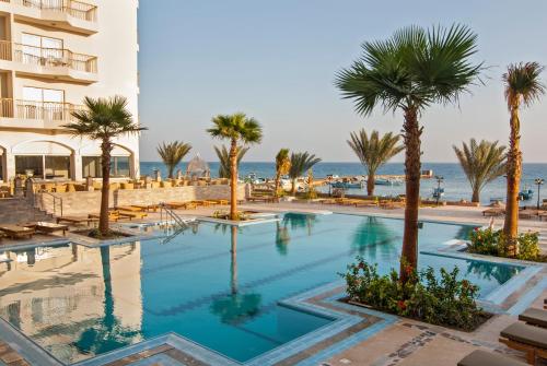 赫尔格达皇家星海滩度假村 的酒店前方的棕榈树游泳池
