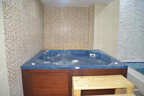 埃尔比勒班诺酒店的一个带木制凳子的浴室内的一个大型蓝色浴缸