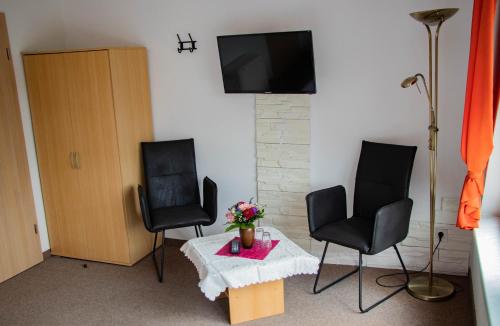 DargunAusflugsrestaurant & Pension Aalbude & Hausfloßvermietung am Kummerower See的客厅配有两把椅子和一张桌子及电视