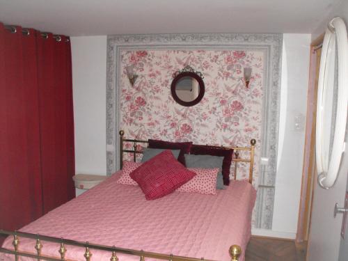 罗什福尔Maisonnette Mimi的一间卧室配有一张带粉色床单和镜子的床