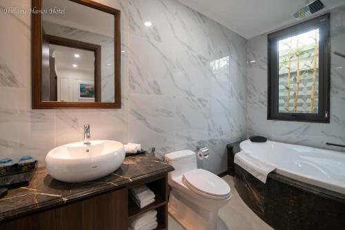 河内Hillary Hanoi Hotel的浴室配有盥洗盆、卫生间和浴缸。