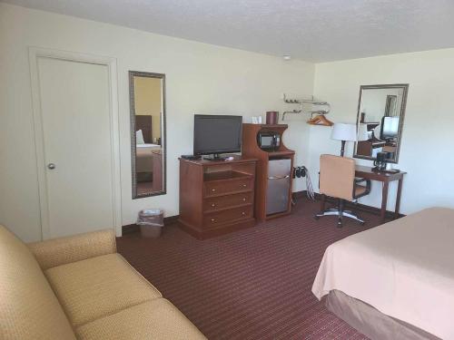 法明顿经济型旅馆 - 法明顿的一间卧室配有一张床和一张书桌及电视