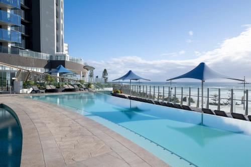 黄金海岸辣椒灵魂冲浪者天堂公寓式酒店的一个带遮阳伞和海洋的游泳池