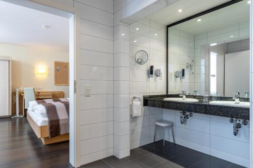 杜塞尔多夫Trip Inn Hotel Esplanade的一间带水槽和镜子的浴室以及一张床