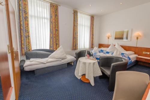 诺德奈Inselhotel Cornelius的酒店客房带两张床和一张桌子以及椅子。
