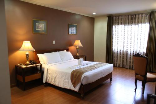 Balanga皇冠皇家酒店 的一间卧室配有一张床、两盏灯和一个窗户。